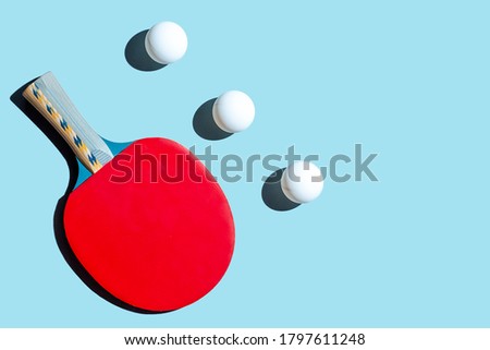Red racket for table tennis with white balls on blue background. Ping pong sports equipment in minimal style. Flat lay, top view, copy space. Royalty-Free Stock Photo #1797611248