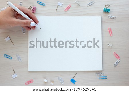 School office supplies on wooden background. Back to school concept. White board with hands for copy space. Top view ready for your design