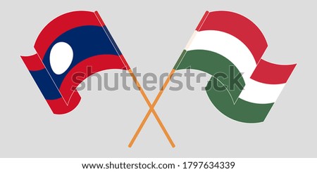 Crossed and waving flags of Laos and Hungary