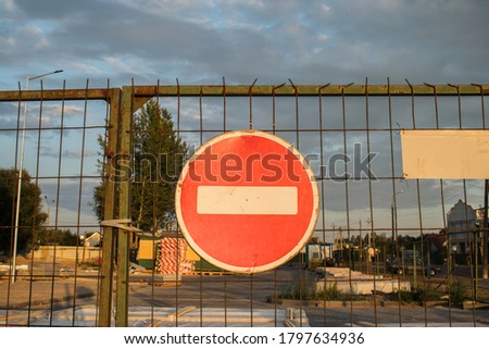 A red round road sign with a white stripe prohibiting traffic on a barred gate. Not enter. the concept of a ban, a dead end, and a stop.
