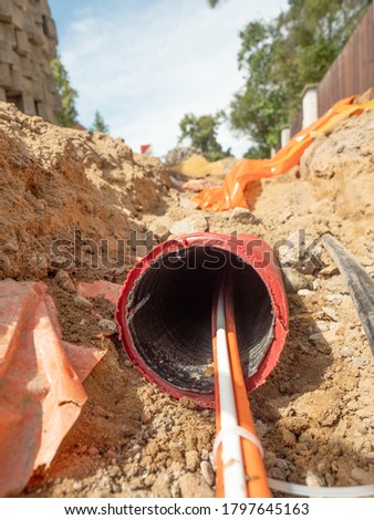 Data fiber optic cables in ribbed pipe under road. Wire in HDPE and protectivep tube. Building of lines of metallic and optic cables,  Royalty-Free Stock Photo #1797645163