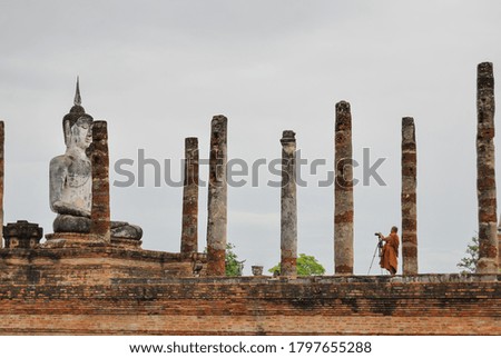 Buddhist monk taking pictures at Wat Mahathat ancient capital of Sukhothai Thailand. UNESCO world heritage