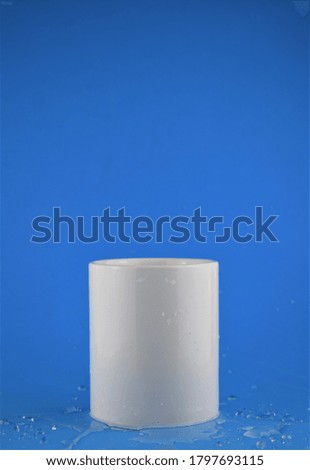 Close-up of a white porcelain cup, blue background, water base and space for text