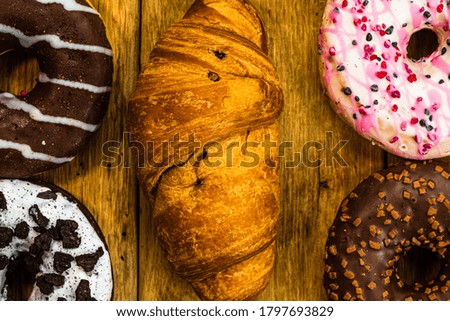Colorful donuts on wooden table. Sweet icing sugar food with glazed sprinkles, doughnut with chocolate frosting. Top view with copy space