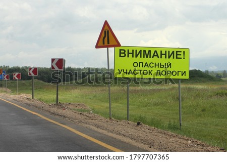 WARNING! DANGEROUS road SECTION - Road sign with Russian inscription on the road side against the background of the lane narrowing signs and the direction of the dangerous turn
