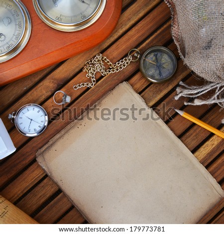 ancient mariner's compass, watch and old paper on wooden background