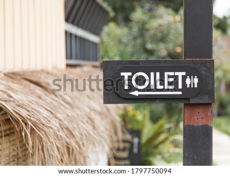 Label of symbol of toilet for men and women on black plate, direction sign and navigation pointer WC restroom out the building.