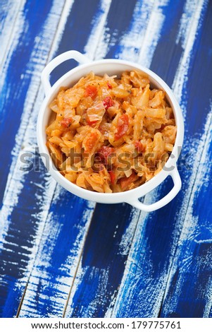 Braised cabbage over blue wooden background, above view