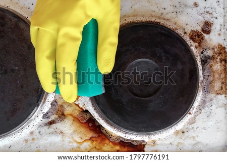 hand in household glove cleaning grease and dirt from kitchen stove Royalty-Free Stock Photo #1797776191