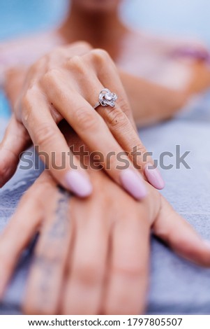 Close shot of womans hands on edge of swimming pool with ring on finger
