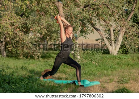 A young woman is engaged in fitness in the fresh air, in an Apple orchard. the concept of a healthy lifestyle. Selective focus.