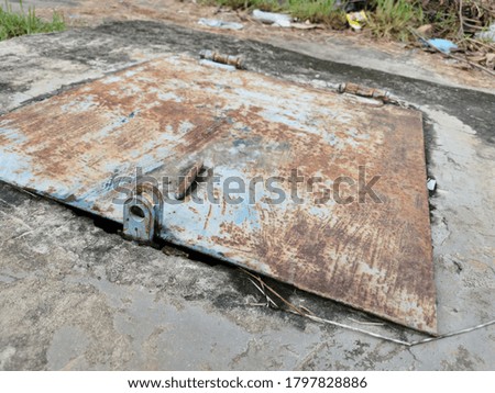 Selective focus on image of old rusty metal cover on concrete floor in the morning.Image has grain or blurry or noise and soft focus.