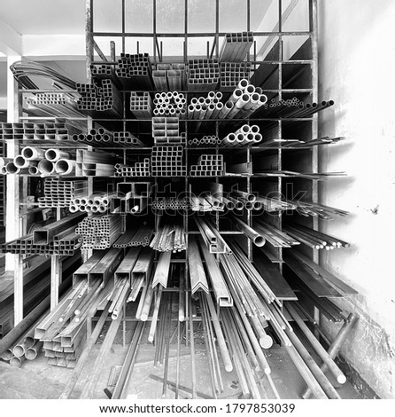 Abstract photo of metal pipes tubes in black and white metalic colors on a rack at the local material shop in rural area of Thailand waiting for the customer to buy it, construction material concept