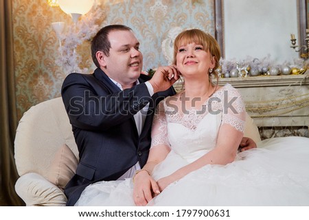 Bride and big fat groom together in a nice room in a wedding day