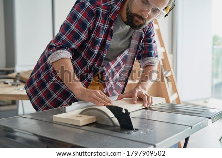 Carpenter in protective glasses cutting with a circular saw                               