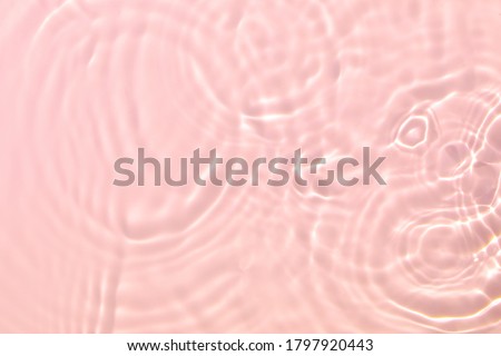 Closeup of pink transparent clear calm water surface texture with splashes and bubbles. Trendy abstract summer nature background. Coral colored waves in sunlight. Royalty-Free Stock Photo #1797920443