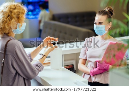 Blond woman washing hands with alcohol gel at reception counter of medical clinic desk Patient hand sanitizer gel to wash hands for virus protection Covid-19 concept. Royalty-Free Stock Photo #1797921322