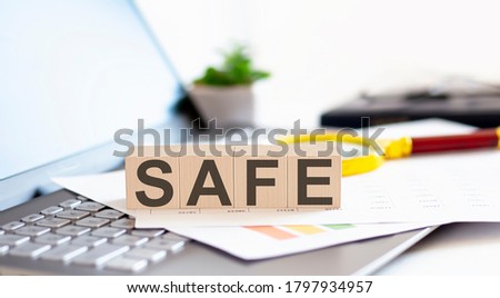 SAFE Wooden cubes with letters on a laptop keyboardwith charts , magnifier