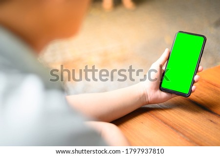 Asian men holding a smartphone in the hands of a green screen green screen at the park