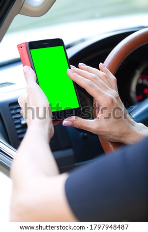 woman driver with a smartphone in her hands while driving