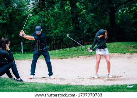 Golf sand practice shots. Young woman having a lesson with golf instructor