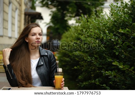 Young woman drinking orange juce in outdoor restaurant