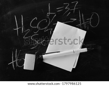 Chemistry formula on black chalkboard with pen and white sheet of paper, blackboard  background and texture