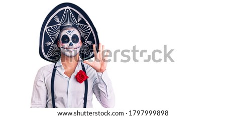 Man wearing day of the dead costume over background showing and pointing up with fingers number five while smiling confident and happy. 