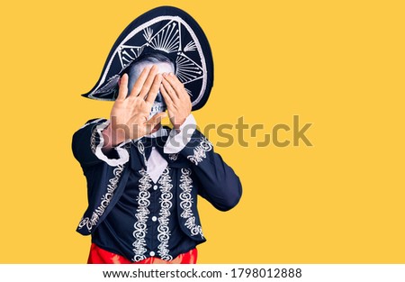 Young man wearing day of the dead costume over background covering eyes with hands and doing stop gesture with sad and fear expression. embarrassed and negative concept. 