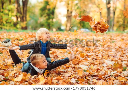 Cute children playing and laughing on autumn walk. Happy brothers throwing autumn leaves outdoors. Autumn vacation. Fashionable kids in park. Kids fashion. Boys playing with leaves. Royalty-Free Stock Photo #1798031746