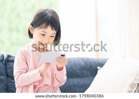 Asian little girl using a smart phone.