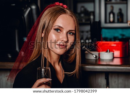 Portrait of young woman sitting at the bar and drinking wine alone