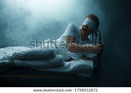 Blindfolded crazy man sitting in bed, psychedelic