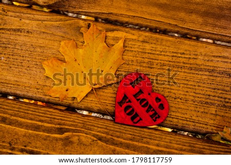 Yellow Autumn maple leafes and red heart  on the wooden backround