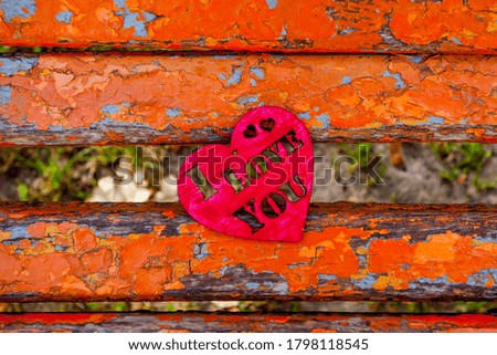 Red wooden heart on the wooden bench background in autumn