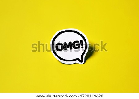 OMG speech bubble on white paper isolated on yellow paper background with drop shadow. COPY SPACE. REAL PHOTO.