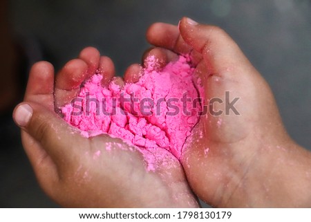 Child hands with dry holi paint.Colour powder for traditional indian festival.Close up photography,copy space.Heart like pink paint.