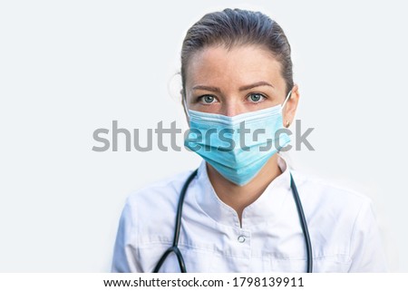 portrait of tired, exhausted young woman doctor with stethoscope, or nurse in mask after work, surgery, procedures on white background in hospital. emotions of medical staff in the clinic