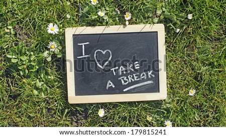 Take a break written on a chalkboard in a park                               