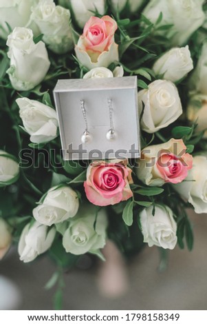 Beautiful wedding jewellery in the white box with pastel pink, yellow roses background. Getting ready bride good morning concept.