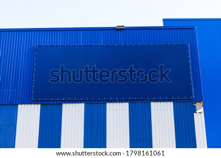 Big empty billboard template on a blue striped building in city