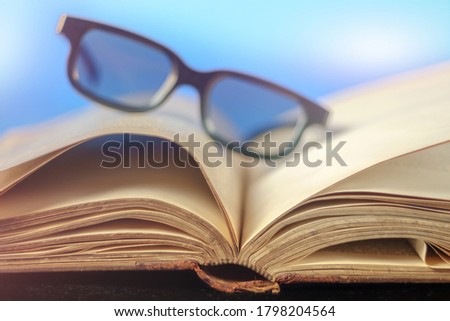 Old vintage opened book with glasses, selective focus