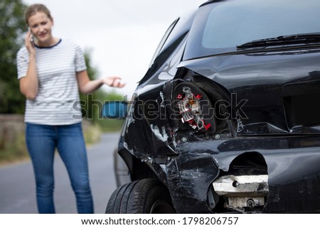 Unhappy Female Driver With Damaged Car After Accident Calling Insurance Company On Mobile Phone Royalty-Free Stock Photo #1798206757