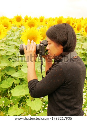 Afro-Asian woman taking a picture of a sunflower field