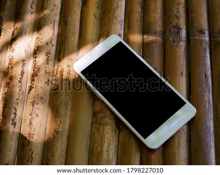 Mockup smart phone black screen on bamboo table top view 