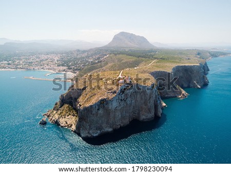 Aerial view photography coastal town of Javea with green rocky mountains, turquoise bay Mediterranean Sea moored vessels in harbour, comarca of Marina Alta in province of Alicante, Valencia, Spain