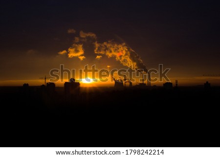 A bright colorful sunset over a thermal power plant in a quiet sleeping area West in Minsk, Belarus. Issues and problems of ecology within the city and beyond. The smoke is illuminated by the sun.
