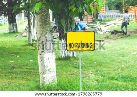 Front view of no parking sign near beach in park against blurred trees and tents background.