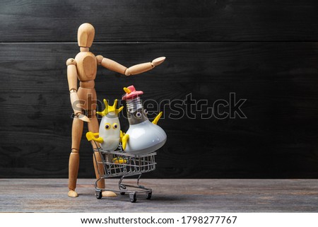 Wooden man carries in grocery carts funny characters made by child from plasticine and energy-saving light bulbs. Do it yourself.