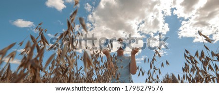 A boy with two round mirrors, in which the sky is reflected in glasses, stands in a field of wheat. Banner